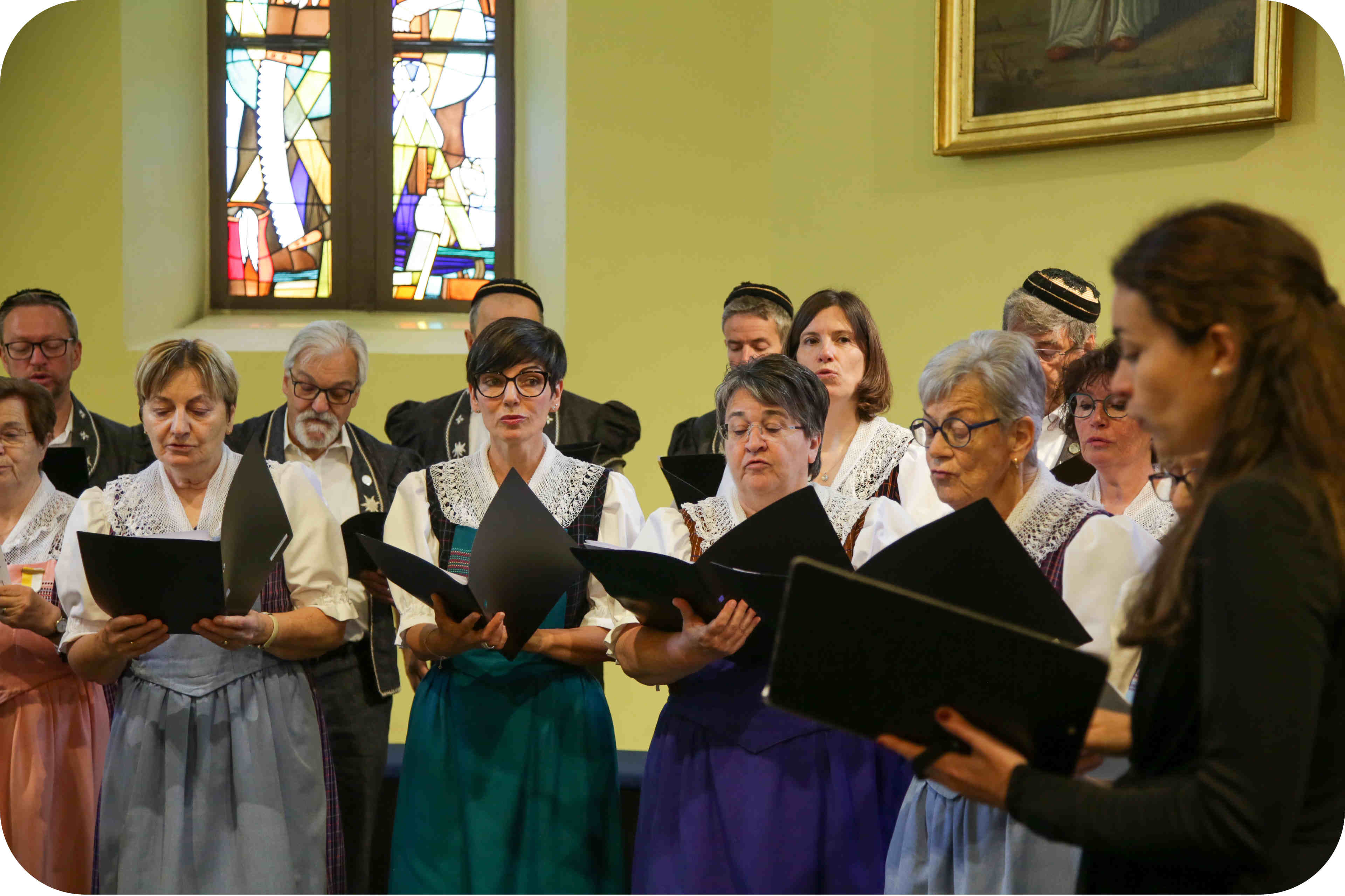 On voit une partie du chœur mixte l’écho de la Sarine, en costume, lors de la remise de Médailles Bene Merenti en l'église de Rossens
